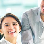 A diverse group of professionals collaborating and smiling during a business meeting, showcasing teamwork and innovation in a modern office environment.
